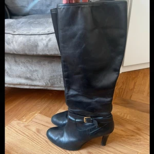 Boots från Ralph Lauren - Klassiska svarta stövletter i skinn från Ralph Lauren med elegant klack och rund tå. Snyggt bälte med guldfärgat spänne vid ankeln och RL-logga under sulan. Perfekta för dig som vill ha en stilren och trendig look. 💗 passar storlek 39-41 skulle jag säga. 