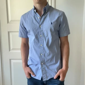 Randig kortärmad Ralph Lauren skjorta - Randig RL skjorta. Inga defekter. Modellen är 180,75 kg och bär S custom fit 