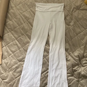 Vita bootcut byxor från Gina Tricot - Snygga vita bootcut byxor från Gina Tricot med stretchigt bomullsmaterial. Byxorna har en bred linning som kan vikas ner och sitter skönt på kroppen. Perfekta för en chill och trendig look.