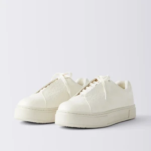 Krämvita sneakers med platt sula - Stilrena sneakers i krämvitt med snörning. Perfekta för dig som gillar en clean stil. 