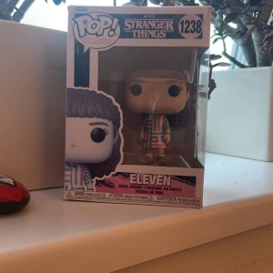 Stranger Things: Eleven (Funko Pop! #1238) - Cool Funko Pop!-figur av Eleven från Stranger Things! Perfekt för fans av serien som vill ha en unik samlarpryl. Eleven bär sin ikoniska färgglada klänning och har detaljerad design. Ett måste för dig som älskar popkultur och vill piffa upp hyllan!