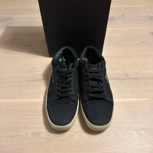 Saint Laurent - Snygga svarta sneakers från Saint Laurent med vit sula och klassisk snörning. Skorna har en stilren design med Saint Laurent-logga på sidan. Perfekta för en trendig och avslappnad look. De är köpta på Plick och det finns inget kvitto därav priset. Lådan hänger med! Priset går att diskutera!