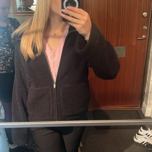 Svart teddyjacka  - Mysig svart teddyjacka med dragkedja framtill. Jackan har en avslappnad passform och långa ärmar, perfekt för kyligare dagar. Prislapp kvar då jag glömde lämna tillbaka, köpte 2! Samma som ni ser på bilderna fast i svart ☺️