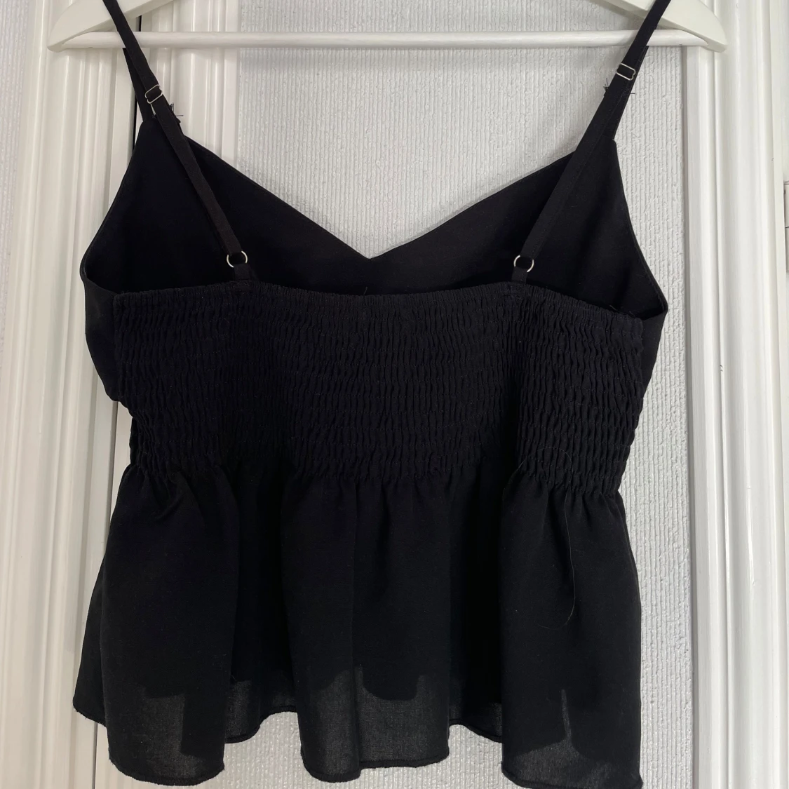 Svart ärmlös topp med smockdetaljer - 1