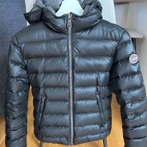 Svart dunjacka från Colmar - Snygg svart dunjacka från Colmar med huva och dragkedja framtill. Superfint skick, kan inte hitta något fel på den alls. Kan skicka fler bilder vid intresse. 