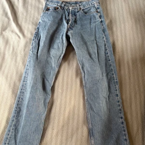 Rocky jeans - Säljer ett par vintage blå jeans från Rocky. De har en rak passform och är tillverkade i slitstarkt denim. Perfekta för en avslappnad stil. Jeansens baksida har en snygg läderpatch med märkets logga. Storlek 44, Innerben 71cm och midja rakt över 37cm. Hög midja. Dessa jeans är pyttelite slitna i låren men absolut inget som syns om man inte kollar jättenoga. Nypris ca 400kr. Pris går att diskuteras.