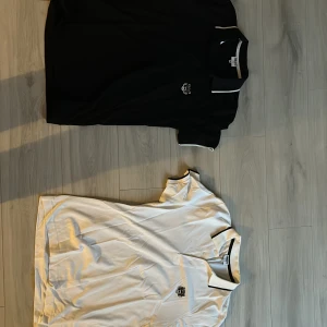 Svart och vit pikétröja från Kenzo - Säljer två stilrena pikétröjor från Kenzo i storlek M. En svart och en vit, båda med broderad tigerlogga på bröstet. Tröjorna har korta ärmar och klassisk krage med kontrasterande kant. Perfekta för en avslappnad men snygg look.