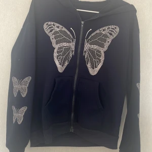 Svart hoodie med fjärilsmönster - Mörk blå hoodie med dragkedja. Fjärilar på framsidan och på armarna.