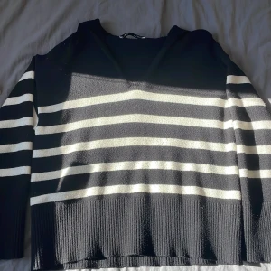 Svart och vit randig tröja från Zara - Säljer en svart och vit randig tröja från Zara. Tröjan har långa ärmar och en ribbad kant vid halsen. Perfekt för en stilren look.