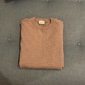 Beige merinoulltröja från John Henric - Säljer en stilren beige tröja från John Henric. Tröjan har en klassisk design med rund hals och är perfekt för både vardag och mer uppklädda tillfällen. Passar utmärkt till lager-på-lager under kallare dagar.