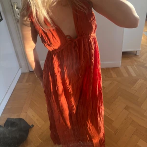 Orange långklänning med djup urringning - Säljer en orange långklänning med djup urringning och knytning framtill. Perfekt till sommaren! I nyskick, tyvärr bara legat i garderoben❣️
