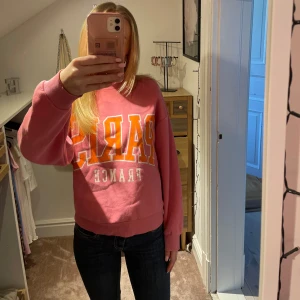 Rosa sweatshirt med Paris-tryck - Säljer en rosa sweatshirt från Gina tricot med texten 'PARIS FRANCE' i stora bokstäver på framsidan. 
