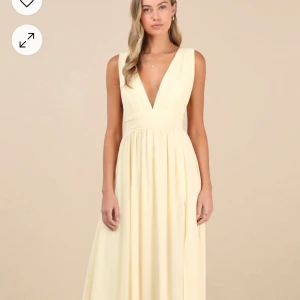 Ljusgul långklänning med v-ringning - Elegant ljusgul långklänning med djup v-ringning och slits. Perfekt för sommarens festligheter. Klänningen har en smickrande passform och är ärmlös för en luftig känsla. Den är slutsåld på hemsidan.