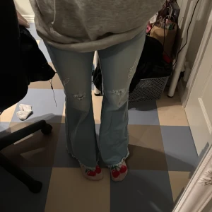 Ljusblå bootcut jeans helt oanvända  - Snygga ljusblå bootcut jeans med slitna detaljer på knäna. De har en klassisk femficksdesign. Perfekta för en avslappnad stil. de är oanvända. igga mina strumpor också tack😝