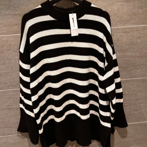  tröja från Gina Tricot - Säljer en snygg svartvit randig stickad tröja från Gina Tricot. Tröjan har en avslappnad passform med långa ärmar och ribbade kanter. Perfekt för en stilren look!