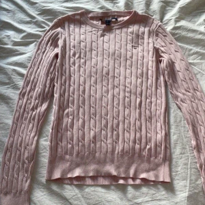 Kabelstickad rosa tröja - Säljer en stilren rosa stickad tröja från GANT med kabelstickat mönster. Tröjan har långa ärmar och en rund halsringning, perfekt för en mysig och elegant look. Passar till både jeans och kjol. 🌸