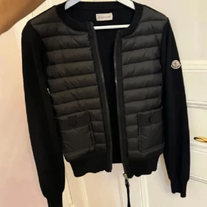 Moncler Cardigan - Snygg svart pufferjacka från Moncler. Jackan har en quiltad design framtill och två praktiska fickor. Perfekt nu till våren. | Inga defekter | Använda max 4-5 gånger |