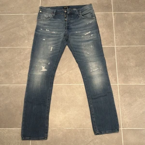 Jack & Jones jeans  - Säljer ett par schyssta jeans från Jack and Jones med snygga slitningar. Modellen heter Glenn Slim Fit(34x32)och sitter snyggt! Vid frågor eller funderingar,tveka inte på att höra av dig!