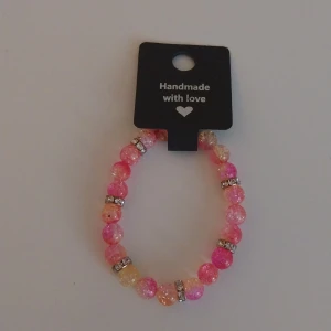 Glittrigt pärlarmband i rosa och gult - Handgjort armband med glittriga pärlor i rosa och gult, dekorerat med silvriga detaljer mellan pärlorna. Perfekt accessoar för att ge din outfit lite extra färg och bling.