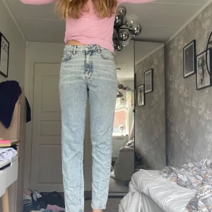 Ljusblå acid wash jeans high waist - Säljer ett par ljusblå jeans med hög midja och raka ben. Jeansen har klassisk femficksdesign, gylf med dragkedja och knapp samt en riktigt snygg vintagekänsla. Perfekta för dig som gillar retrostil och vill ha ett par bekväma jeans med cool tvätt.