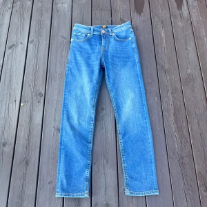 Blåa Jack and Jones jeans - Klassiska Jack and Jones jeans i mellanblå tvätt med raka ben och normal passform. Jeansen har fem fickor, gylf med dragkedja och snygga detaljer på bakfickorna. Perfekta för dig som gillar en tidlös och avslappnad look.