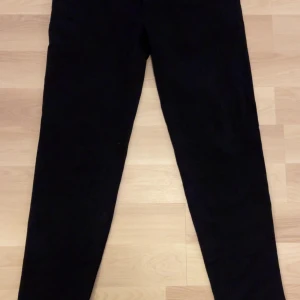 Svarta kostymbyxor Emporio Armani - Helt nya! Snygga svarta kostymbyxor från Emporio Armani i klassisk rak modell. Byxorna har en stilren look och är tillverkade i ett mjukt tyg som känns lyxigt. Perfekta för dig som vill ha en clean och dressad vibe.