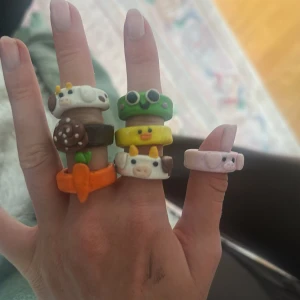 Färgglada djurringar i lera - Sju handgjorda ringar i lera med söta djurmotiv: ko, groda, gris, anka, snigel och morot. Ringarna är i olika färger som grön, gul, vit, brun, orange och rosa. Perfekt för dig som vill ha något unikt och lekfullt på fingrarna. Skriv sen vilken ni vill ha 50kr/styck