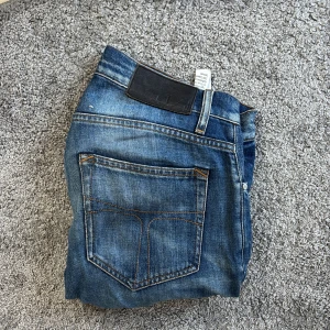 Blå jeans tiger of Sweden 29/32 - Säljer ett par klassiska blå jeans från tiger of Sweden. Jeansen har snyggt slitna detaljer och raka ben. Tillverkade i denim och passar dig som gillar en tidlös denimlook.