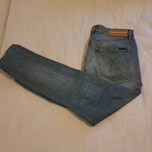 Ljusblå Calvin Klein jeans W34 L34 - Snygga ljusblå jeans från Calvin Klein Jeans i klassisk rak modell. Jeansen har fem fickor, diskreta slitningar på knäna och tydliga logodetaljer bak i midjan. Tillverkade i bomullsdenim med en avslappnad vibe. Köpt för 999