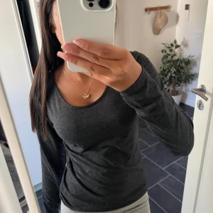 Mörkgrå långärmad tröja från Amisu - Säljer en enkel och stilren mörkgrå långärmad tröja från Amisu. Tröjan har rund halsringning och en slim passform som sitter snyggt på kroppen. Perfekt basplagg till garderoben och funkar året runt.