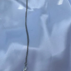 Silverhalsband med vit pärla - Ett stilrent halsband i silverfärgad kedja med en droppformad vit pärla som hänge. Perfekt för dig som gillar minimalistiska smycken med en elegant touch.