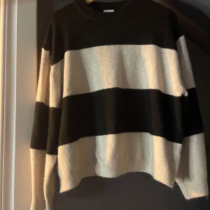 Randig svartvit stickad tröja - Säljer en oversized stickad tröja med breda svarta och vita ränder. Tröjan har rund halsringning och långa ärmar. Perfekt för dig som gillar en chill och avslappnad stil. Materialet är mjukt och känns riktigt skönt mot huden.
