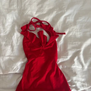 Röd tröja från Miss Poem - Supersöt röd tröja från Miss Poem med volangdetaljer och knyt i ryggen. Klänningen har v-ringning och är ärmlös, perfekt för sommarens varma dagar. Mjuk och lätt i materialet, sitter snyggt och framhäver figuren.