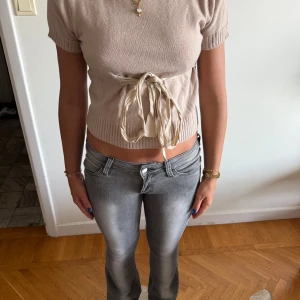 Beige stickad topp med knytband - Snygg beige stickad topp med korta ärmar och croppad passform. Hör av dig för flera frågor/bilder 