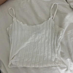 Vit ribbad linnetopp från SHEIN - Säljer en vit ribbad linnetopp från SHEIN i storlek XS. Toppen har smala axelband och raka kanter upptill och nertill. Materialet är mjukt och lätt, perfekt för varma dagar. Enkel och stilren design som är lätt att matcha med olika outfits.