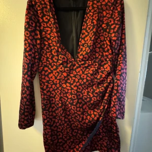 Röd leopardklänning från H&M Divided - Snygg kort klänning från H&M Divided med rött leopardmönster på svart botten. Den är förstor på mig och ja har använt den på min födelsedag endast 