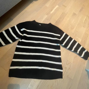 Svartvit randig stickad tröja - Säljer en svart stickad tröja med vita horisontella ränder. Tröjan har en rund halsringning och långa ärmar. Den är ribbstickad och har en avslappnad passform.