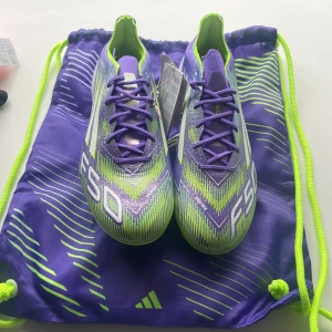 Adidas F50 lila och lime fotbollsskor - Säljer Nyaste färgen i ett par Adidas F50 fotbollsskor i en riktigt fet färgkombo av lila och limegrönt. Skorna har snörning, mönstrad ovandel och tydliga F50-loggor. Yttersulan är delvis transparent med limefärgade dobbar. Kommer med matchande skopåse och extra innersulor. Diskuterar gärna pris! 