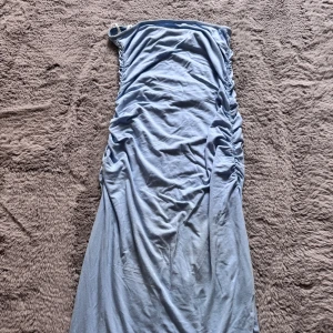 Ljusblå långklänning med rynkade sidor - Säljer en ljusblå långklänning med en axelbandslös design och snygga rynkade detaljer längs sidorna. Klänningen har en mjuk och följsam passform. Köpt på shein använd några par gånger.