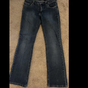 Mörkblå bootcut jeans - Snygga mörkblå jeans med klassisk bootcut passform. Jeansen har fem fickor, låg midja och subtila slitningar för en avslappnad look. Perfekta till sneakers eller boots och tillverkade i mjukt denimtyg.