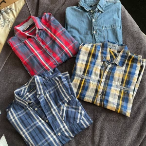 4 rutiga skjortor från Livergy - Fyra  rutiga skjortor från Livergy i olika färgkombinationer: en i rött och blått, en i blått och vitt samt en i blått, gult och grått. Och en jeans skjorta.Alla har klassisk krage, knappar framtill och bröstficka. Perfekta för dig som gillar avslappnad och stilren look.