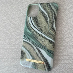  iDeal of Sweden iPhone 11 PRO MAX skal  - Snyggt mobilskal från iDeal of Sweden med marmor-inspirerat mönster i grönt, vitt och guldiga toner. Skalet har en lyxig känsla med guldfärgad logga och passar perfekt för dig som vill ha en trendig look på mobilen.