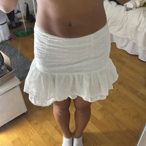 Vit volangkjol från SHEIN XS - Supersöt vit kortkjol från SHEIN i storlek XS. Kjolen har broderade små blommor, volangkant nertill och dragkedja bak. Perfekt för sommarens alla tillfällen och ger en fräsch och feminin vibe.