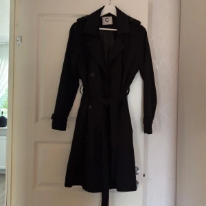 Svart trenchcoat med bälte - Svart trenchcoat med bälte från Cubus i storlek M. 
