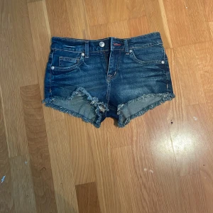Mörkblå jeansshorts med fransig kant - Låg midjade. Aldrig använda . Strl 34