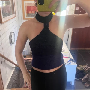 Marinblå virkad halterneck topp - Säljer en marinblå virkad halterneck topp med bred halsringning som knäpps runt nacken. Toppen har öppen rygg, perfekt för dig som gillar unika och handgjorda plagg. Snygg att styla med både jeans och kjol. Jag har gjort den själv. Passar ca storlek 38