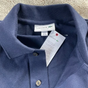 Mörkblå pikétröja från Lacoste - Hejsan!! Säljer en Lacoste piké som är perfekt på golfbanan. Pikén har aldrig använts men fortfarande ett väldigt bra pris och prisförslag mottas! Kontakta vid intresse👌🏼
