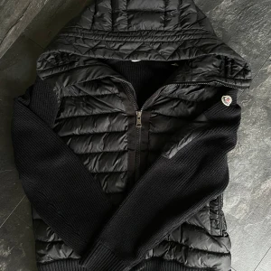 Moncler Cardigan - Hej säljer en jätte fin Moncler Cardigan i Storlek L, men passar även storlek M. Väldigt fin i skick, men har ett litet litet hål på luvan, märks knappt (Bild 4). Vid några frågor eller funderingar är det bara att höra av sig! /Alex