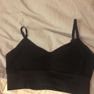 Svart ribbad linnetopp med smala band - En svart ribbad sportöverdel med smala, justerbara axelband och bred resår nedtill. Materialet är stretchigt och bekvämt för en snygg och avslappnad look. Aldrig använd!❤️