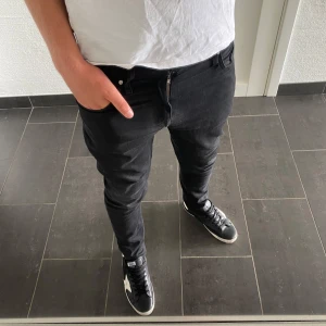  Tiger of Sweden jeans - Säljer ett par svarta jeans från Tiger of Sweden, modell Pistolero. De har en slim passform med klassisk femficksdesign och dragkedja. Jeansen är tillverkade i bomull med lite stretch för extra komfort. Perfekta för dig som gillar en stilren och modern look.